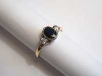 18ct yellow and white gold three stone ring set with oval cut sapphire and diamonds in a rubover setting